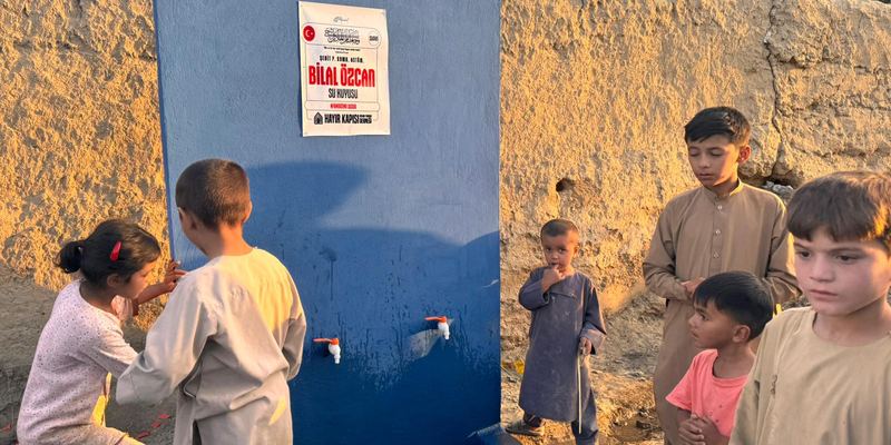 Afganistan’daki su kuyusunun musluğundan su içen çocuklar